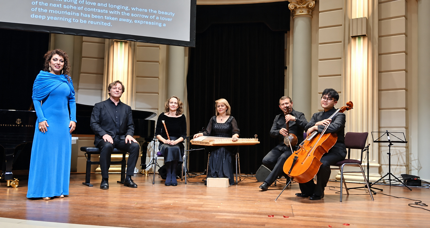 Natali Boghossian standing in her blue gown with the five Zartonk Consort instrumentalists and their instruments on the Concertgebouw stage.